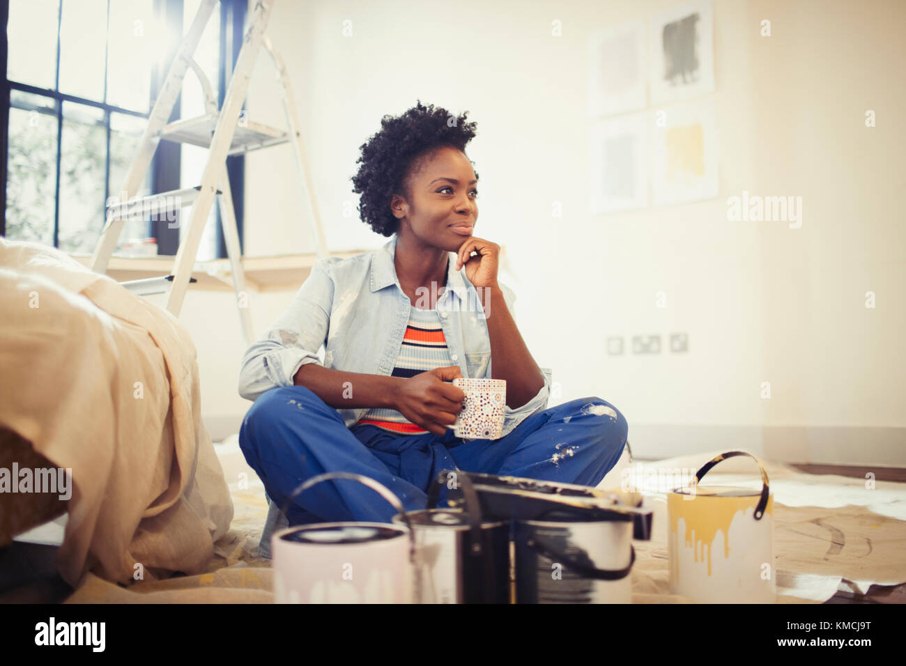 Satisfied woman drinking coffee and painting living room Stock Photo