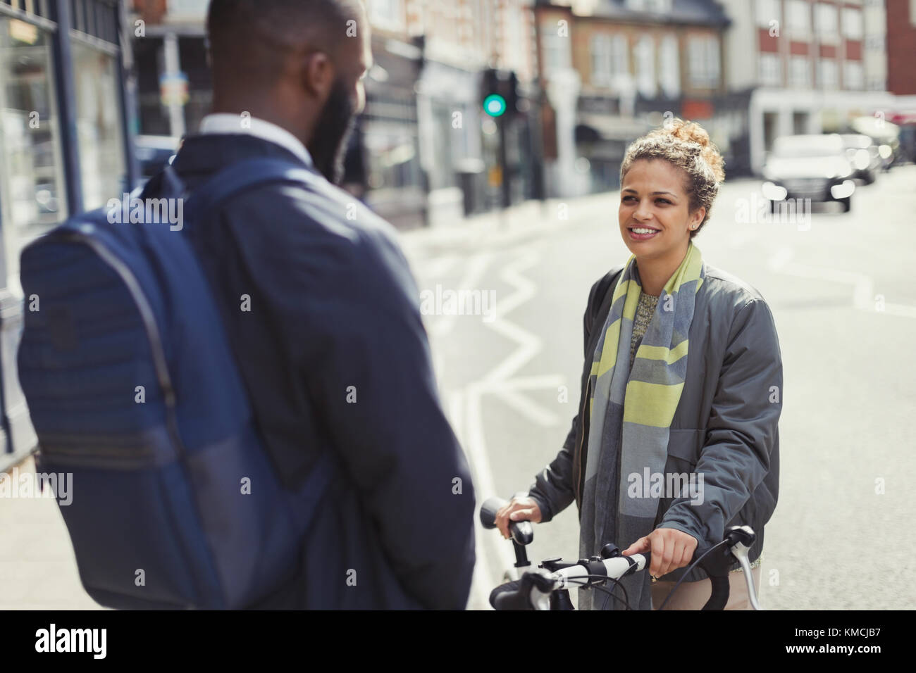 Friends with bicycle talking on sunny urban street Stock Photo