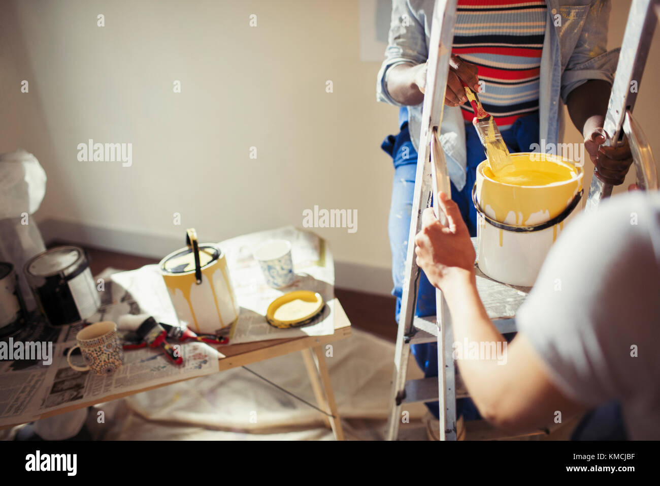 Women with yellow paint painting living room Stock Photo