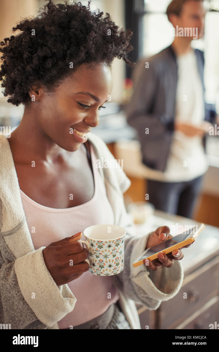 Smiling woman drinking coffee, texting with smart phone Stock Photo