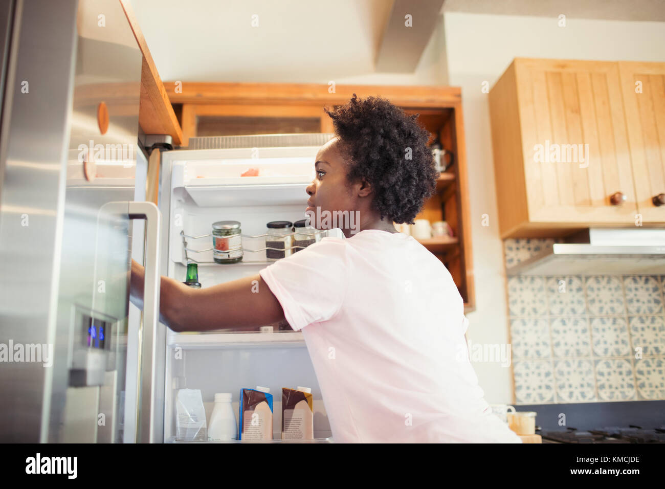Woman reaching into refrigerator in kitchen Stock Photo