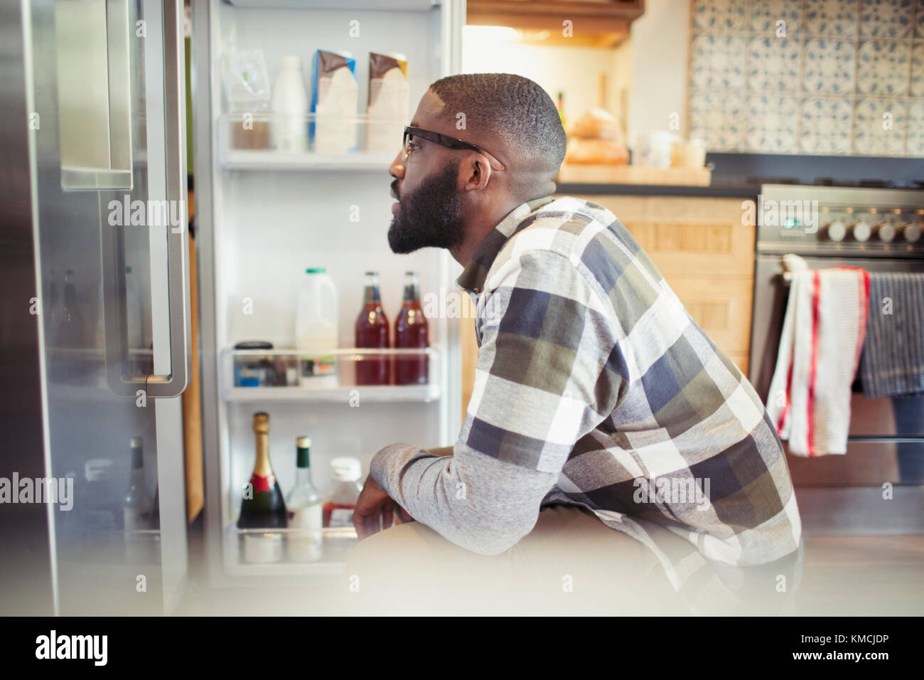 Hungry man peering into refrigerator in kitchen Stock Photo