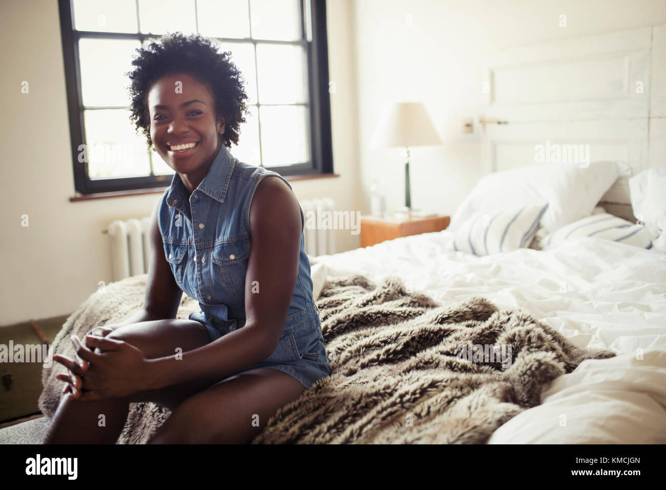 Portrait smiling, confident woman sitting on bed Stock Photo