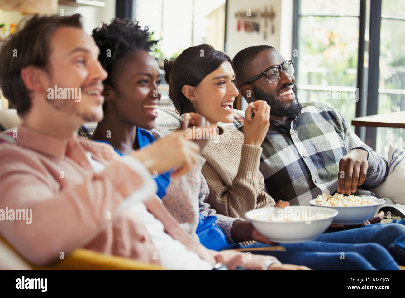 Smiling couples watching movie, eating popcorn Stock Photo