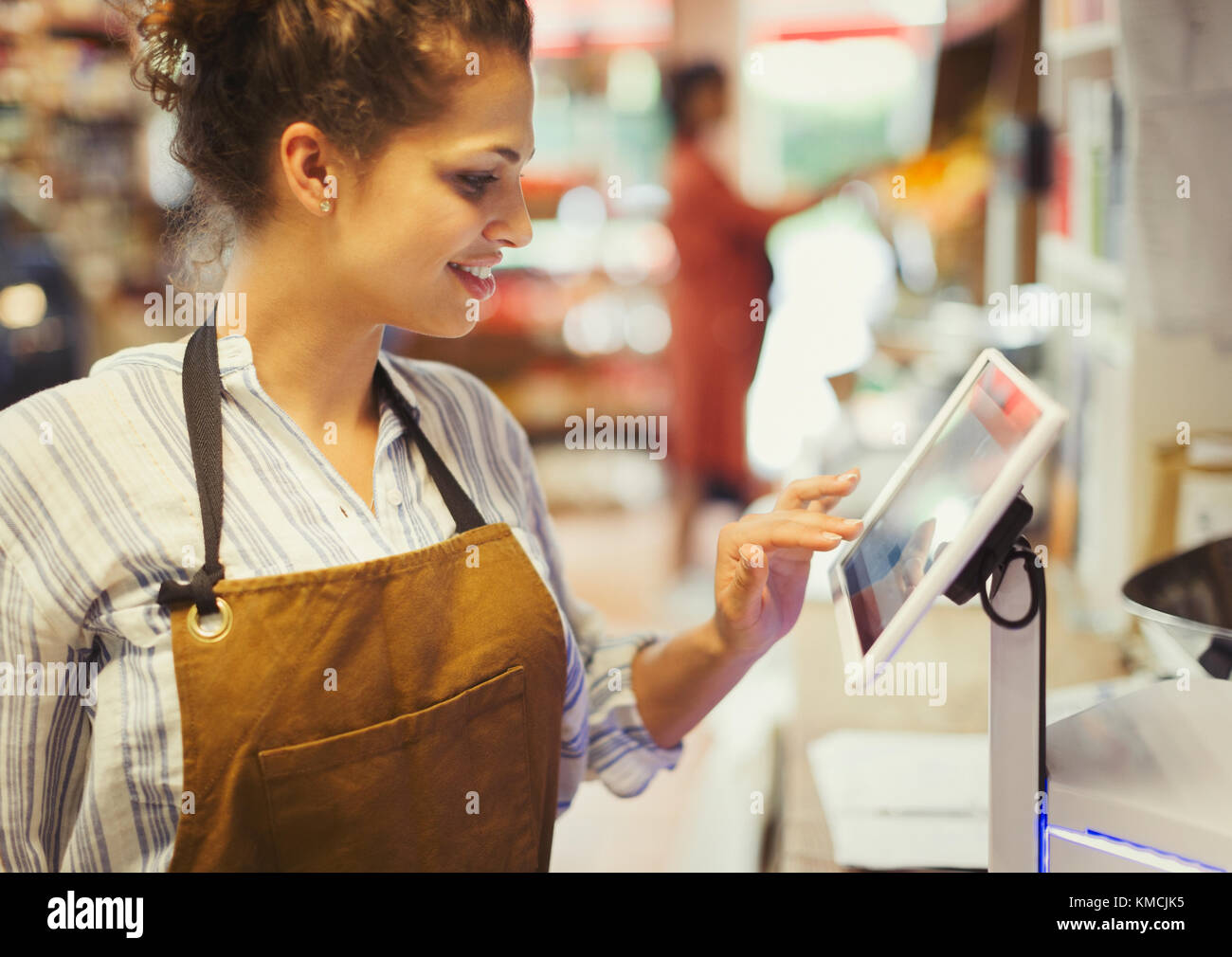 Female cashier using touch screen cash register in grocery store Stock Photo