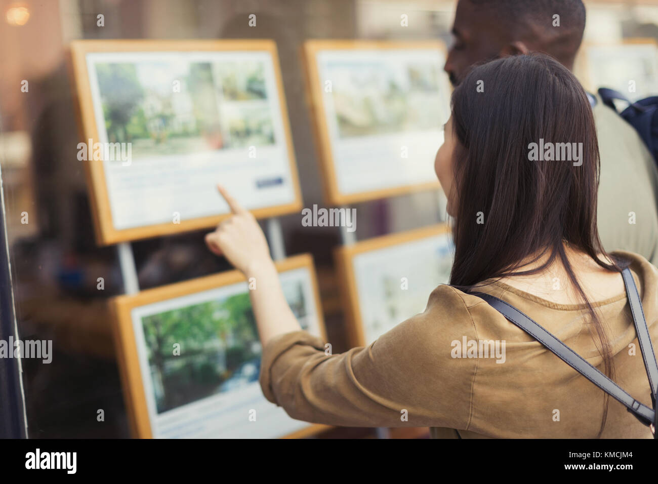 Young couple browsing real estate listings at storefront Stock Photo