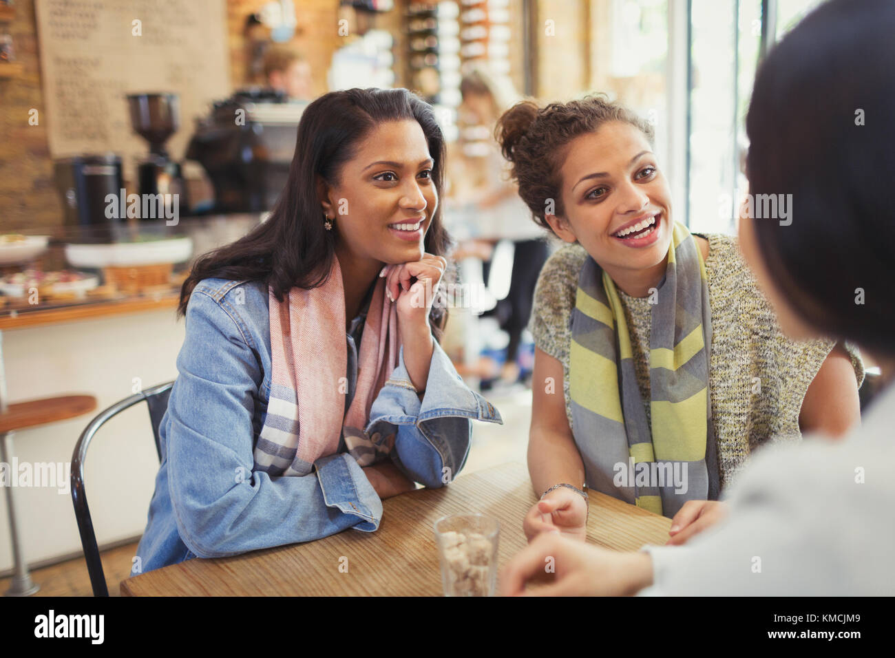 Smiling women friends talking at cafe table Stock Photo