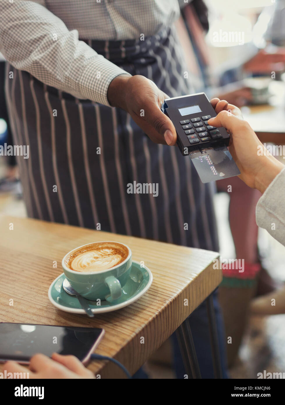 Customer paying waiter with credit card reader at cafe table Stock Photo