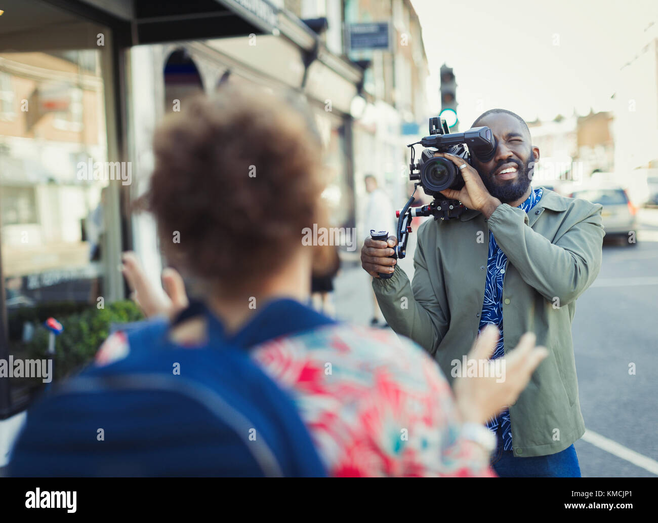 Young man with video camera videoing woman on street Stock Photo
