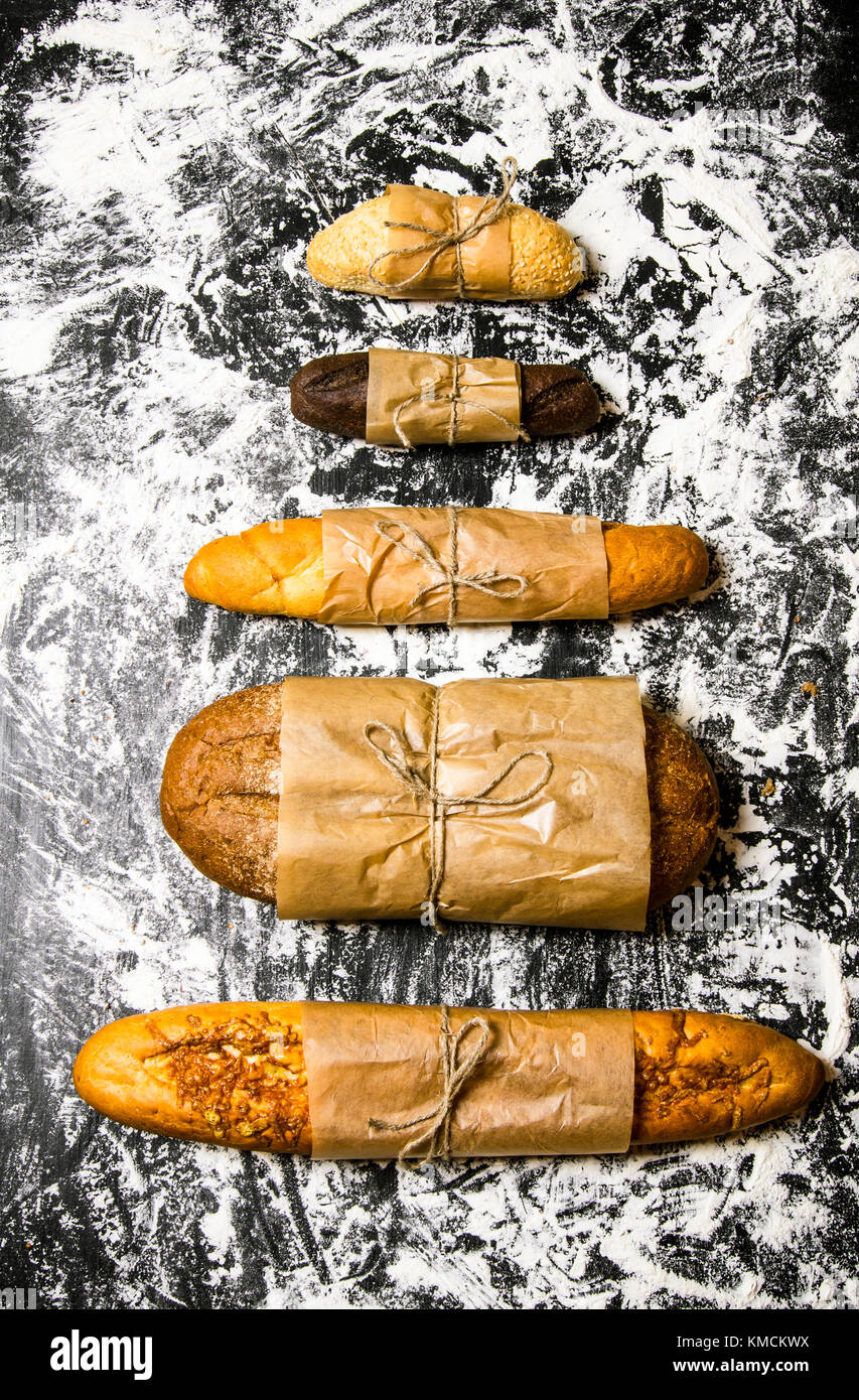 Set of fresh bread wrapped in paper. on the Board with flour. Top view ...