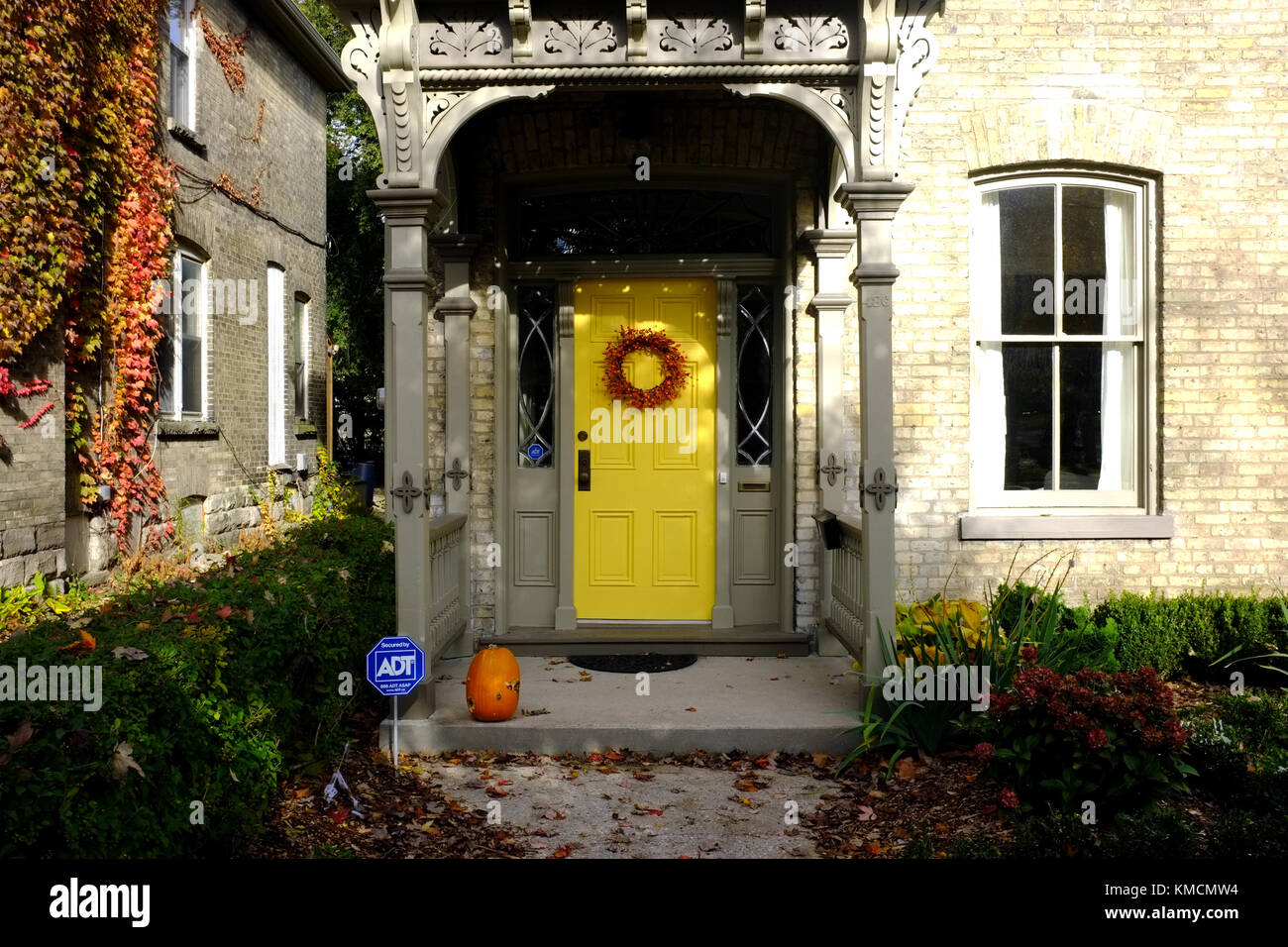 A yellow front door with an Autumnal wreath on it in Ontario, Canada. Stock Photo