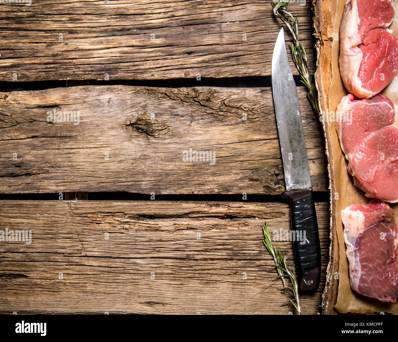 Pieces of raw meat with a butcher knife. On wooden background. Free