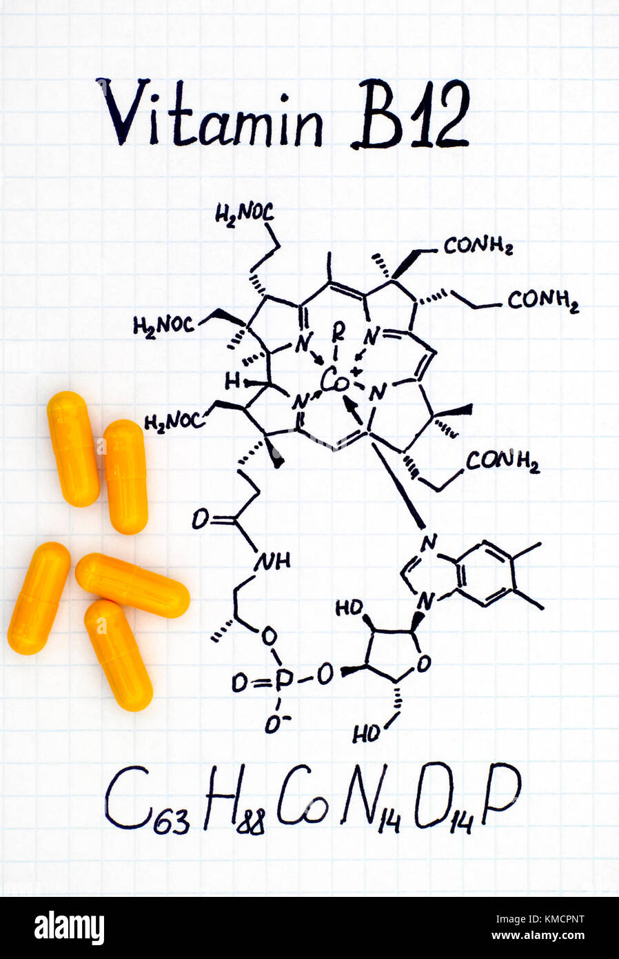 Chemical formula of Vitamin B12 and yellow pills. Close-up Stock Photo