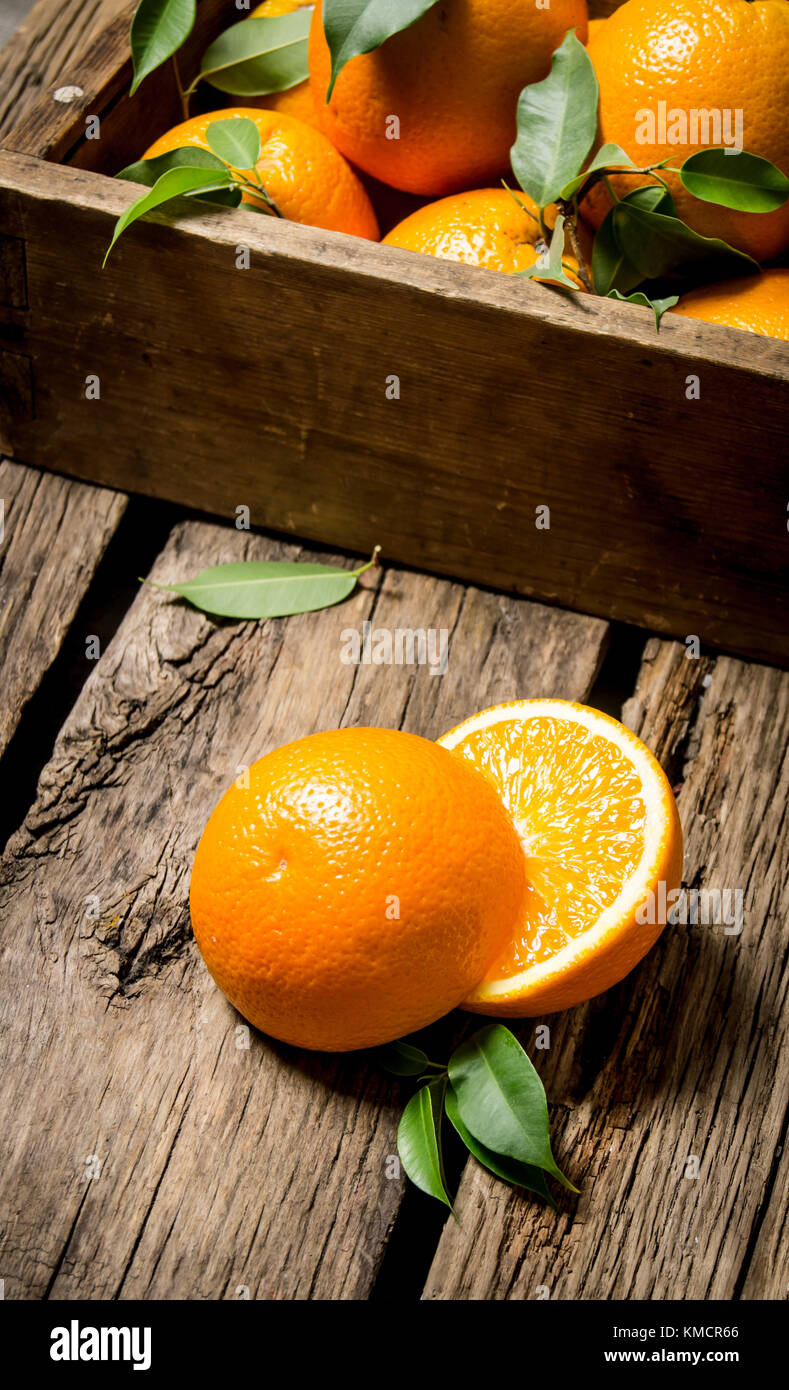 Oranges with leaves in an old box. On a wooden table Stock Photo - Alamy