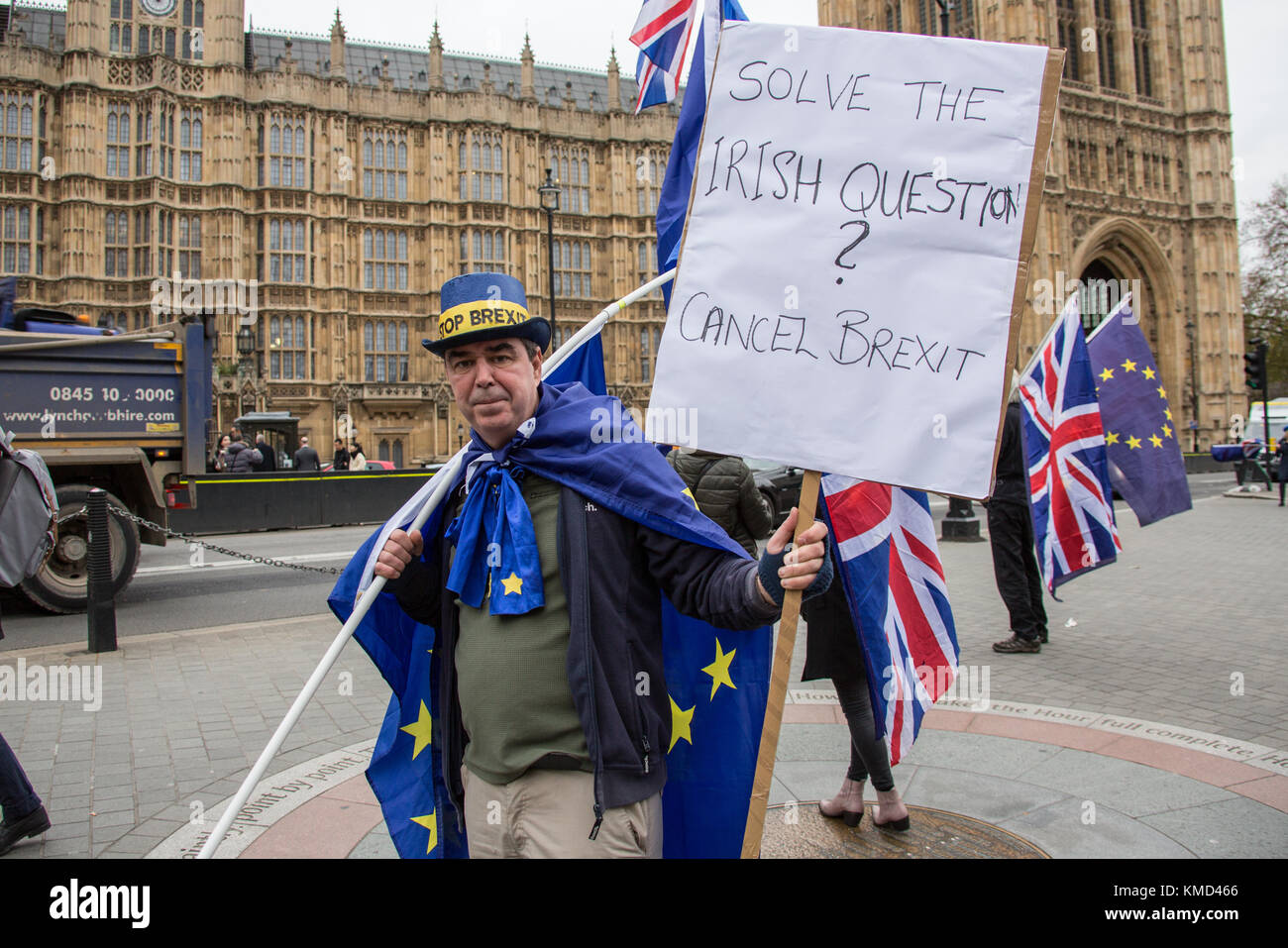 London, UK. 6 December 2017. 'Solve the Irish question, cancel brexit'. Protester Stephen Bray wearing a Stop Brexit hat, holds a placard in one hand and flags of the European Union and a Union Jack in the other during a 'Stop Brexit' demonstration  outside of Parliament. David Rowe/Alamy Live News. Stock Photo