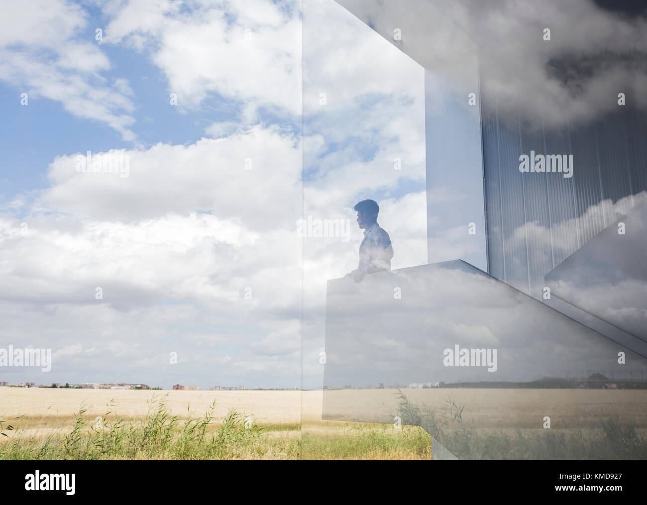 Pensive businessman on modern landing looking out window at sunny blue sky and clouds Stock Photo