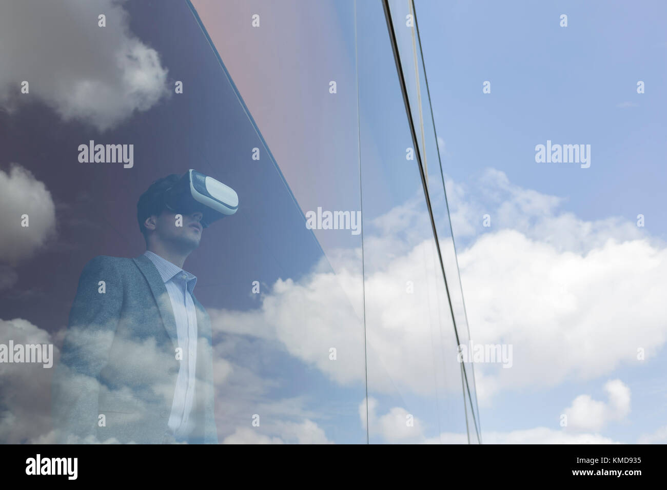 Businessman using virtual reality simulator at modern office window overlooking blue sky and clouds Stock Photo