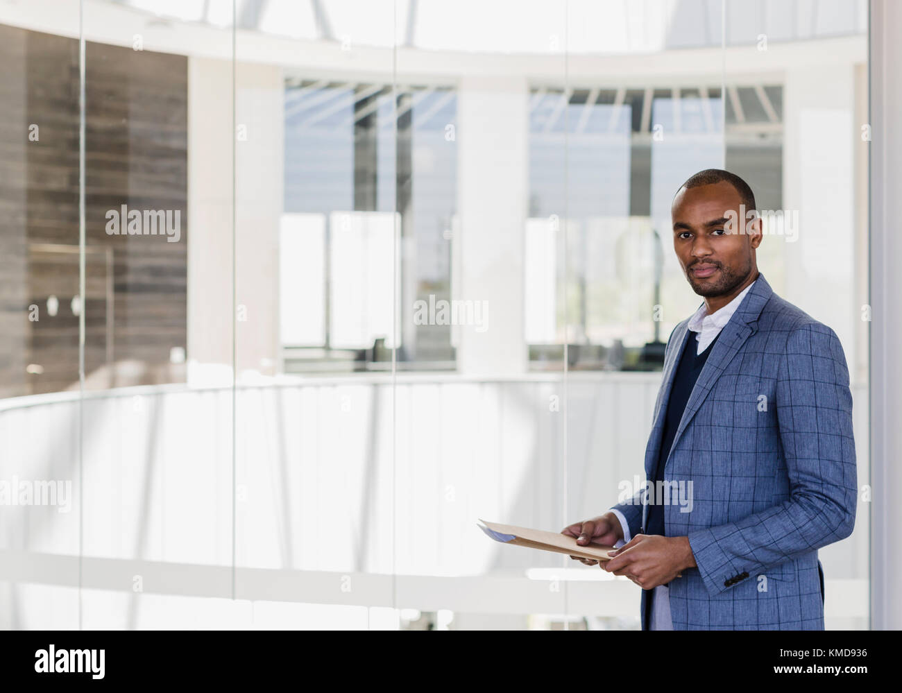 Portrait confident businessman with paperwork in office atrium Stock Photo