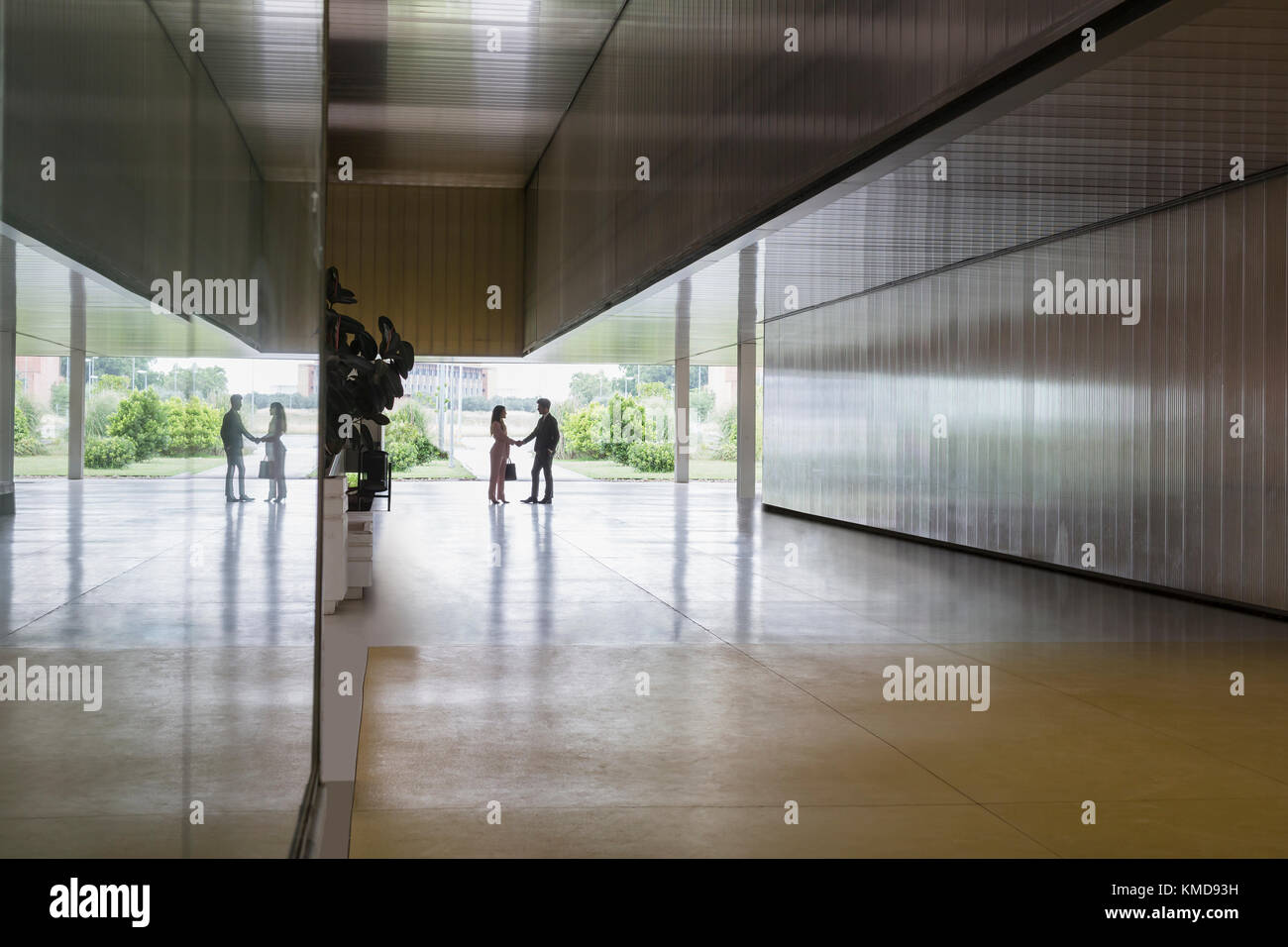 Silhouette businessman and businesswoman handshaking in modern office corridor Stock Photo