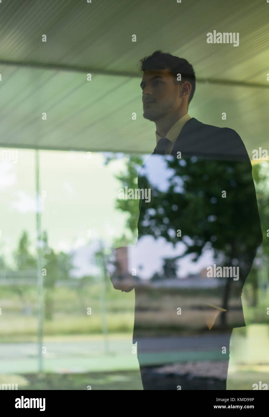 Pensive businessman looking out office window Stock Photo