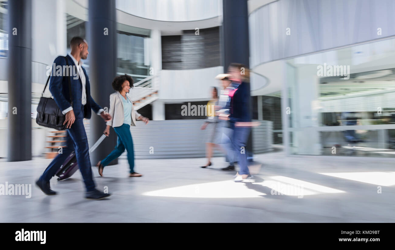 Business people walking,pulling suitcase in modern office lobby Stock Photo