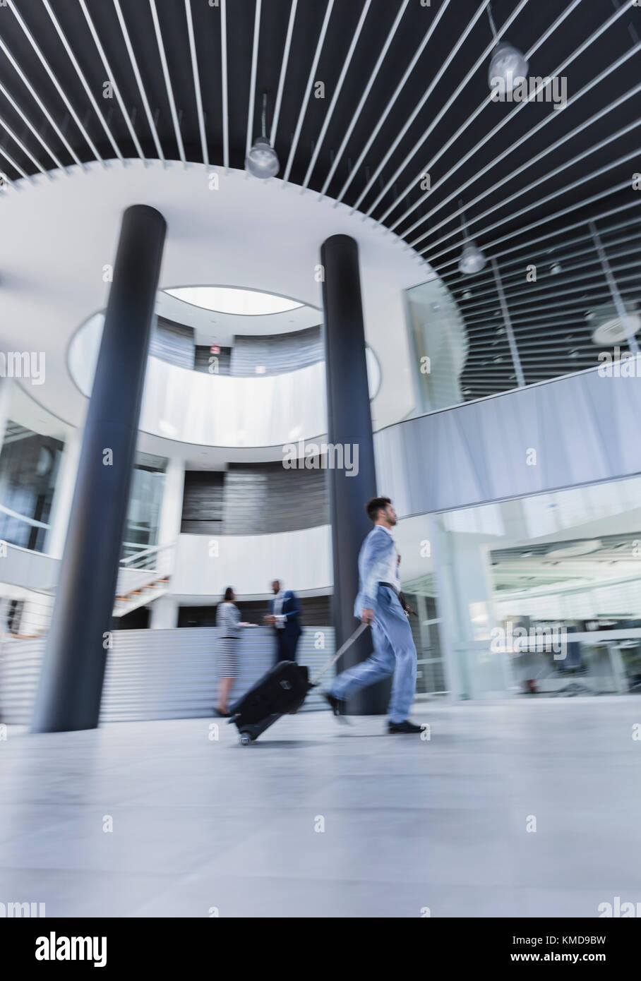 Businessman walking,pulling suitcase in architectural,modern office lobby Stock Photo
