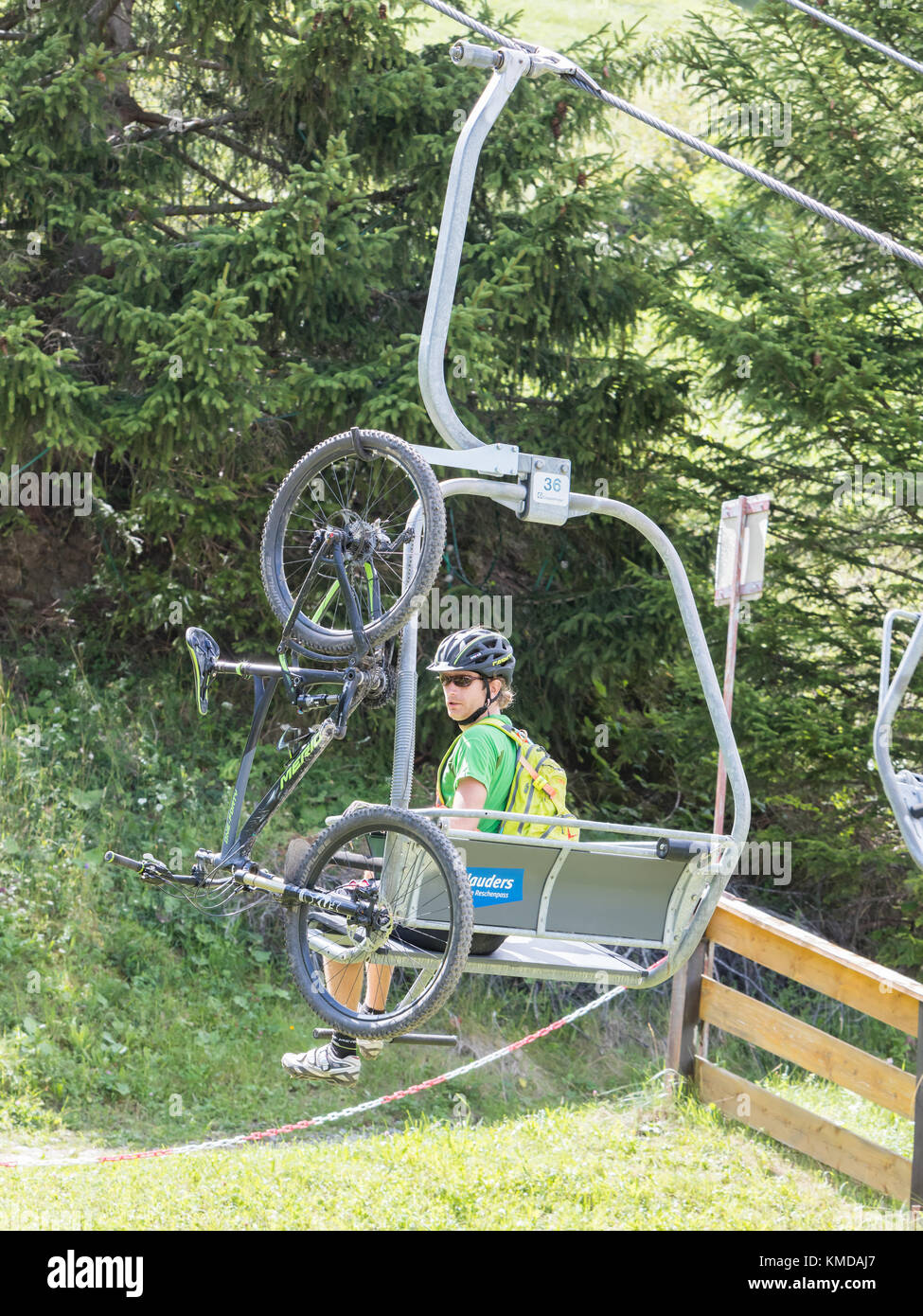 Nauders, Austria - August 4, 2017: Man with a mountainbike sitting in one of the many ski lifts in the Nauders area, summer sports. Stock Photo