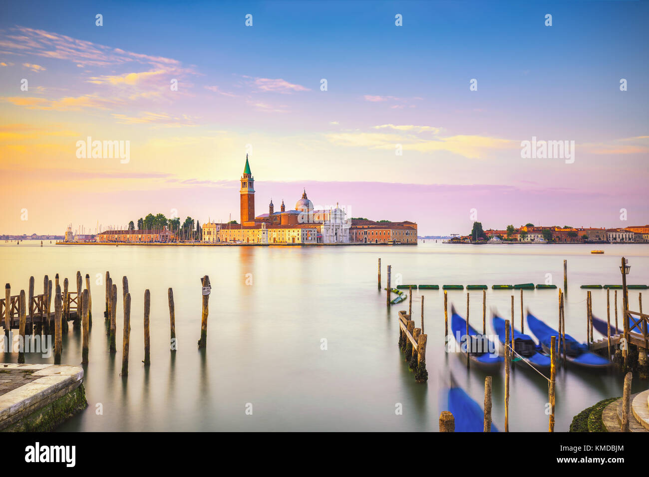 Venice lagoon at sunrise, San Giorgio Maggiore church, gondolas and poles. Italy, Europe. Stock Photo