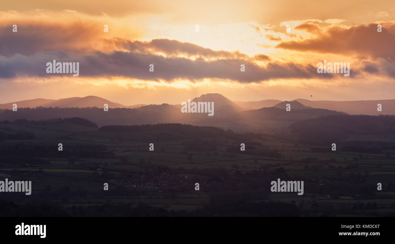 Sun beams through cloudy sky and hills at sunset over hilly countryside in UK Stock Photo