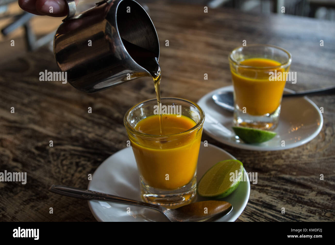 Adding honey to two healthy jamu shots in close-up Stock Photo