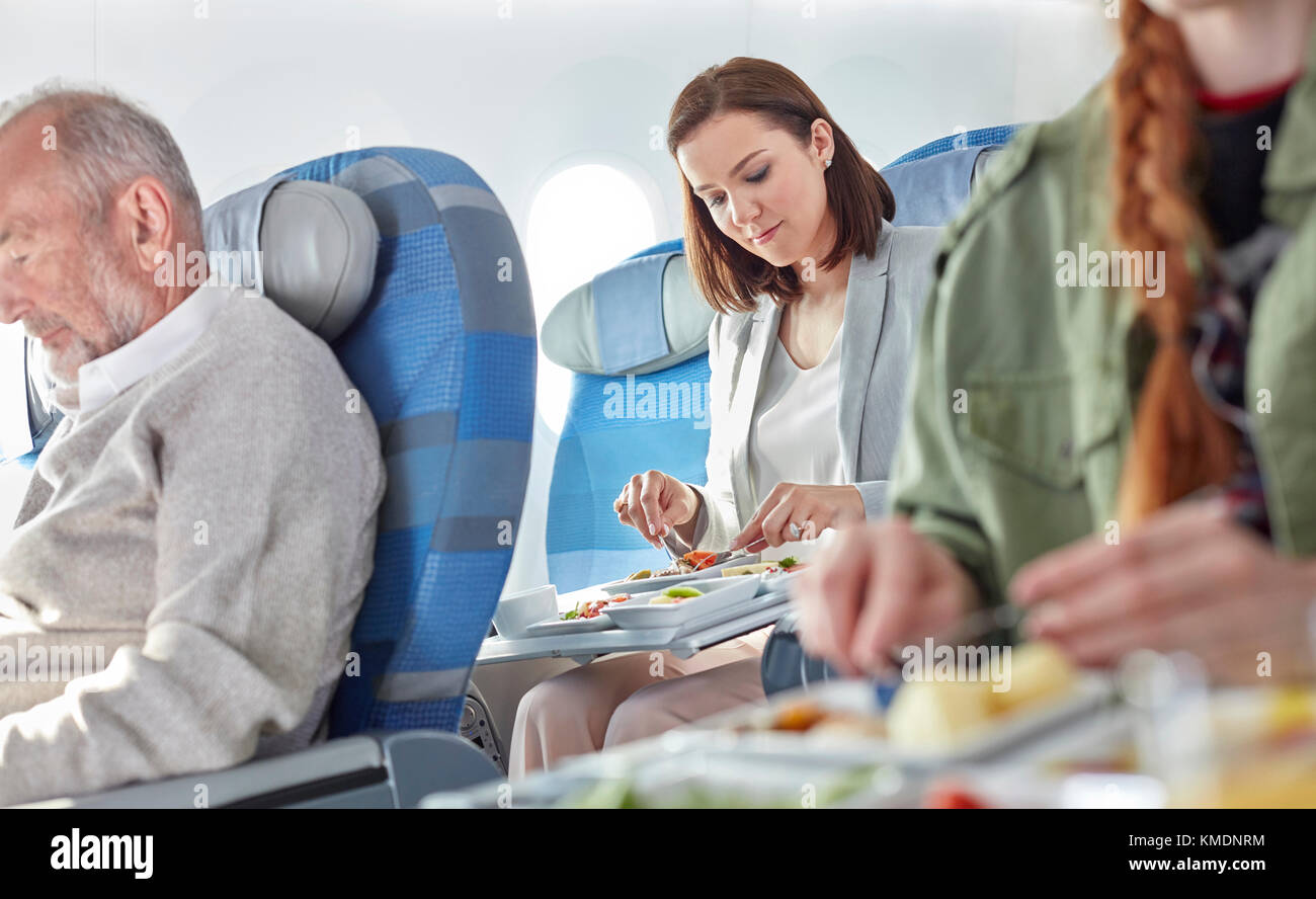 Woman eating dinner on airplane Stock Photo