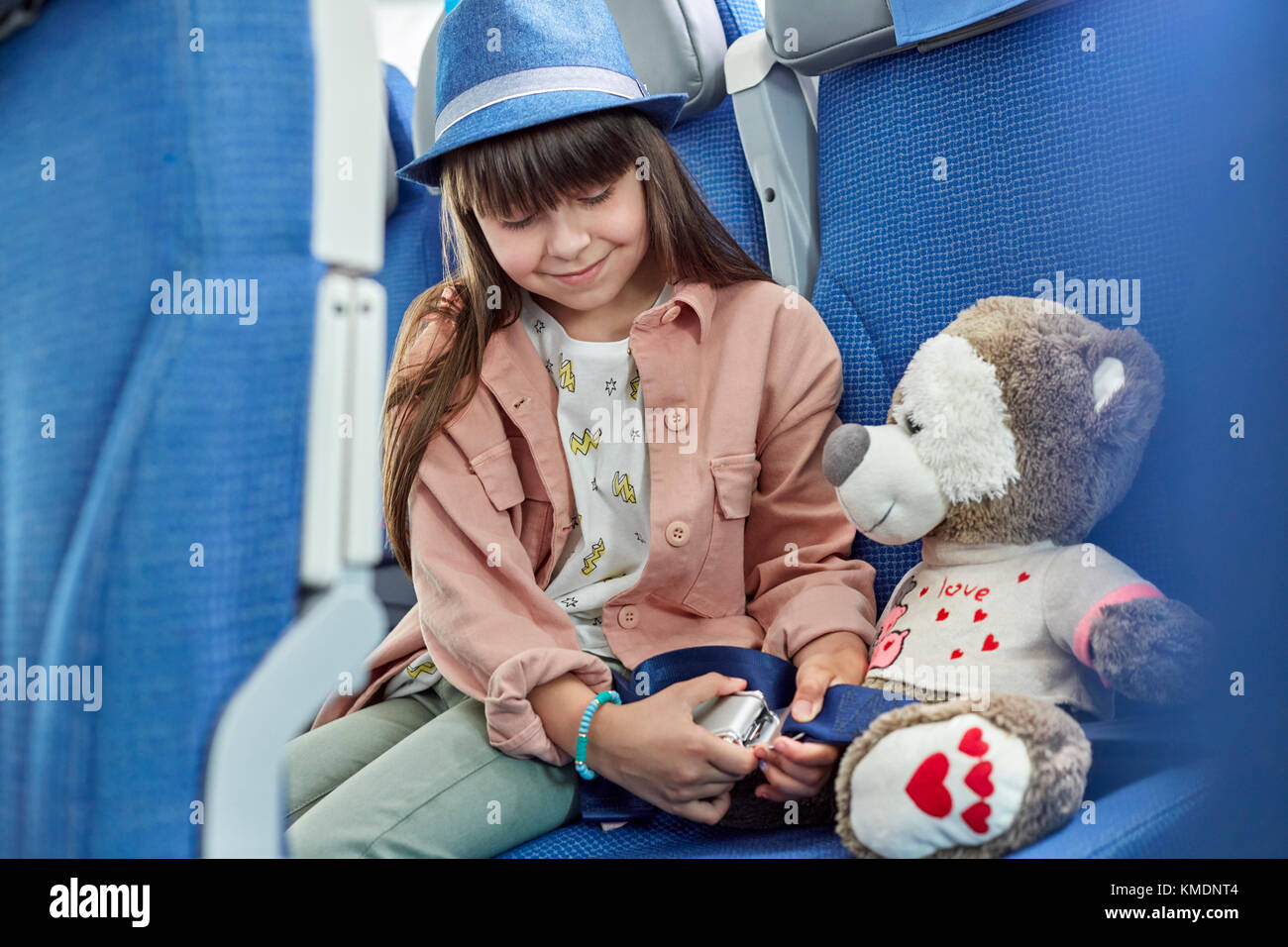 Girl fastening seat belt on stuffed animal on airplane Stock Photo Alamy