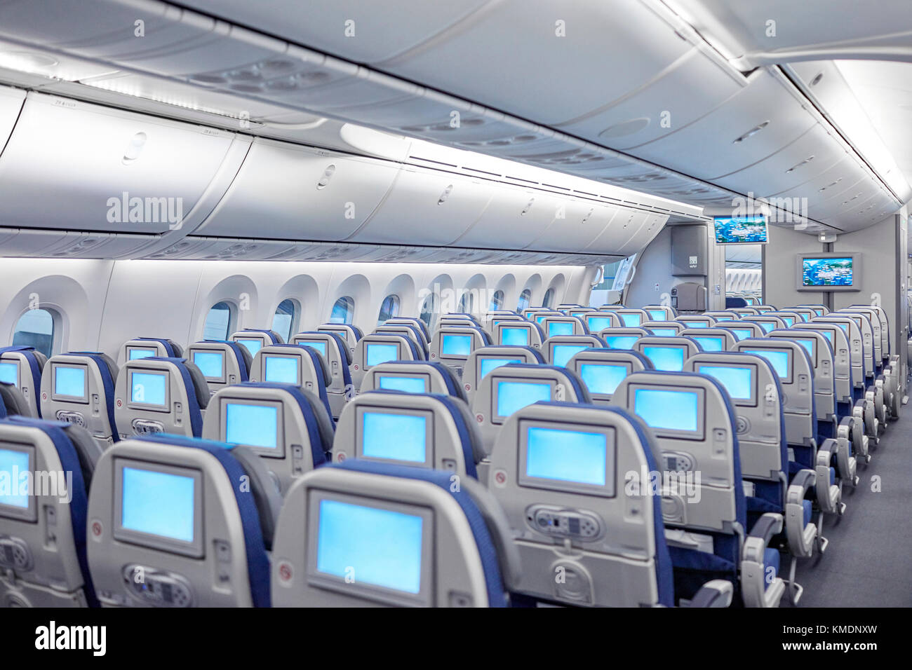 Rows of seats with entertainment screens on airplane Stock Photo