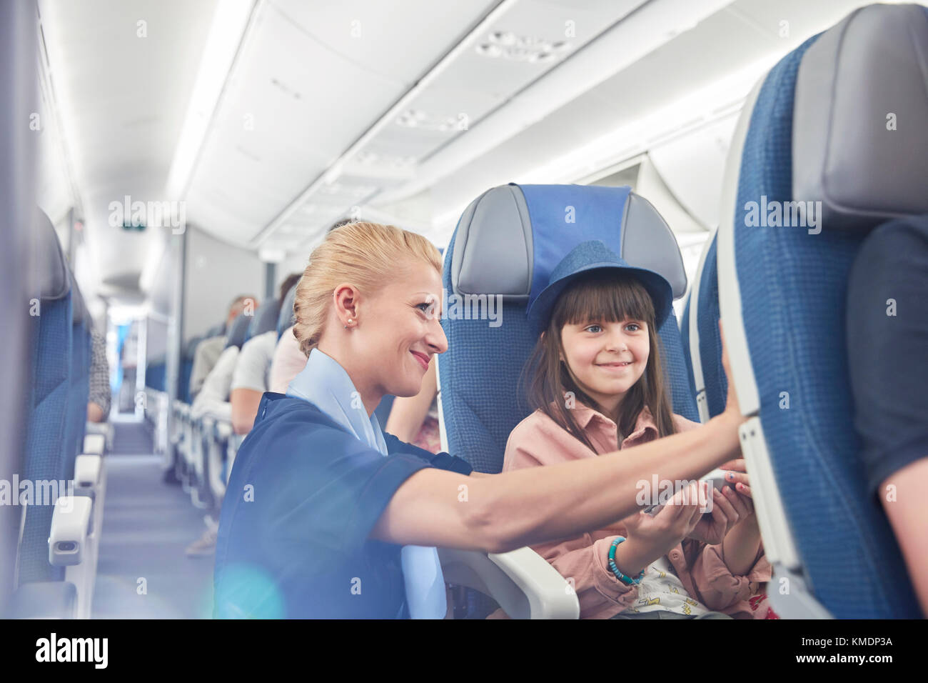 Flight attendant helping girl passenger on airplane Stock Photo