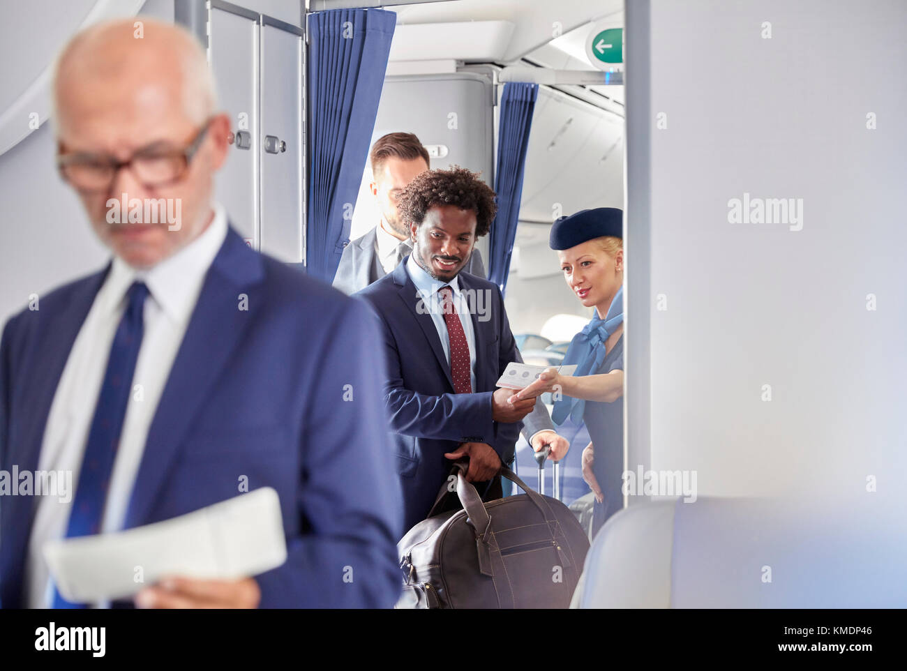 Flight attendant helping businessman with boarding pass on airplane Stock Photo