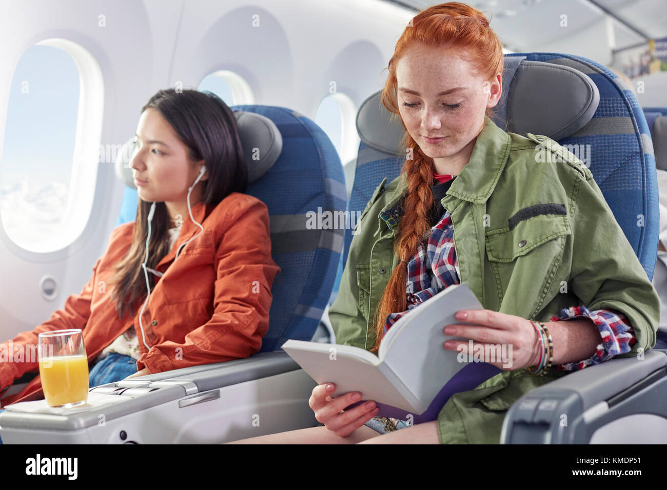 Young woman reading book on airplane Stock Photo