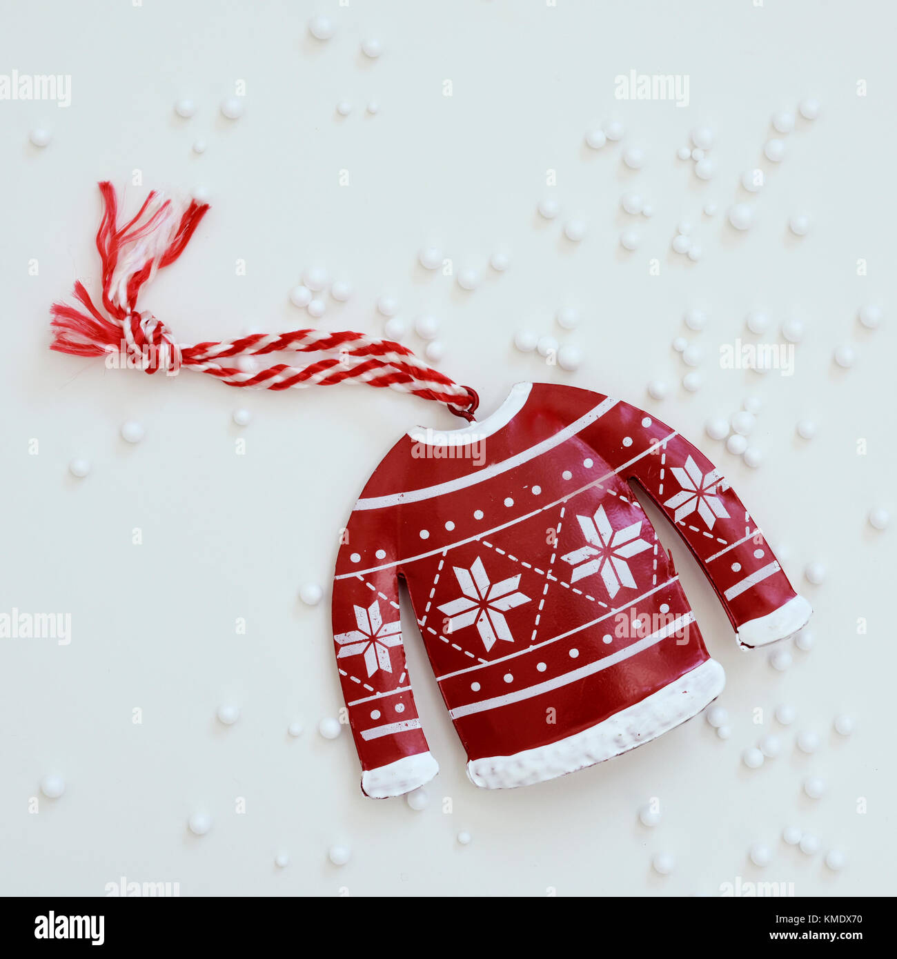 high-angle shot of a christmas ornament placed on a white surface sprinkled with small plastic balls simulating snow Stock Photo