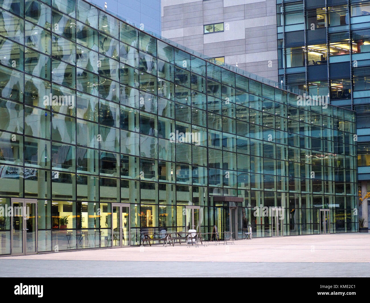 distorted reflections in curve of glazed facade of modern building at