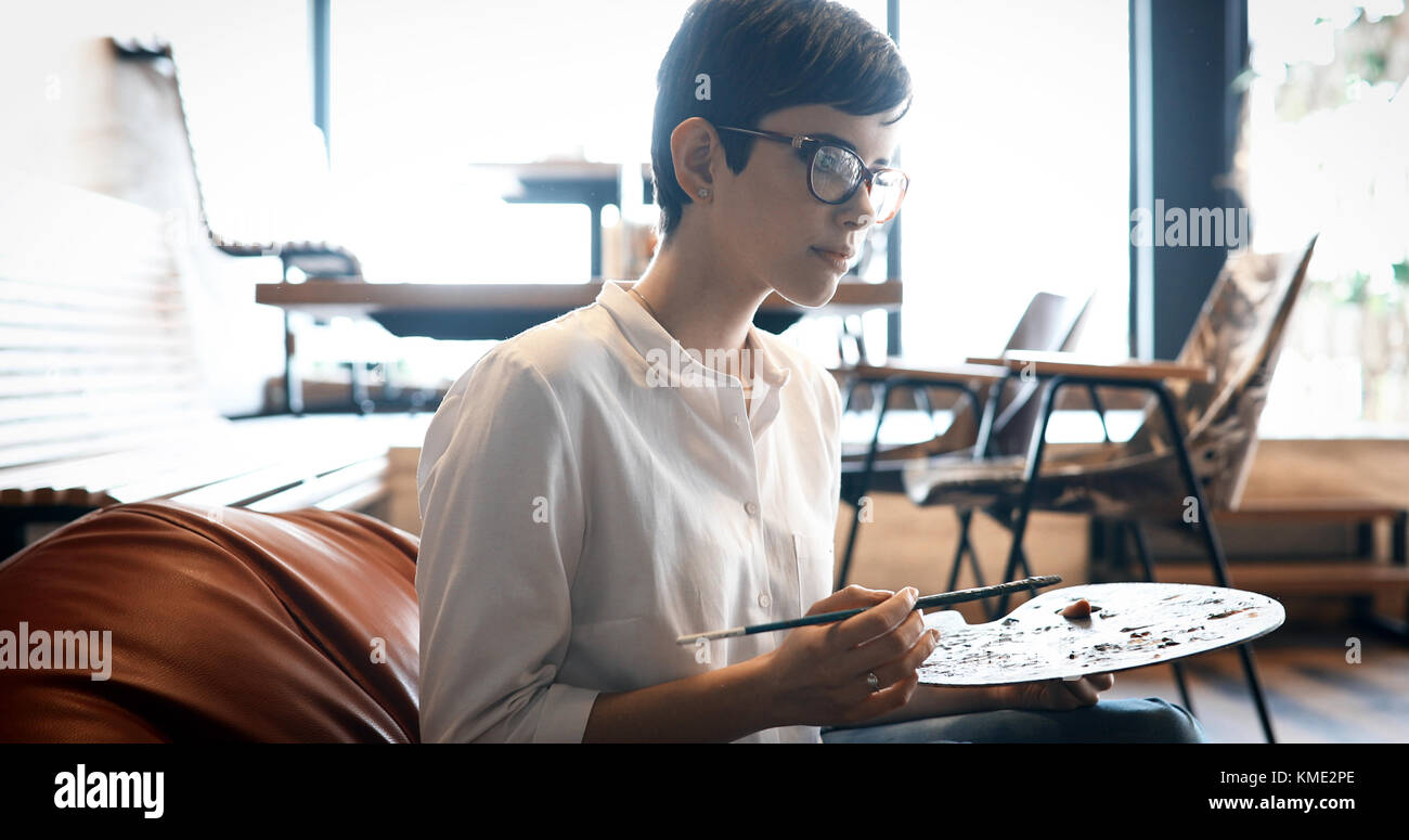 Female artist painting with palette and paintbrush Stock Photo - Alamy