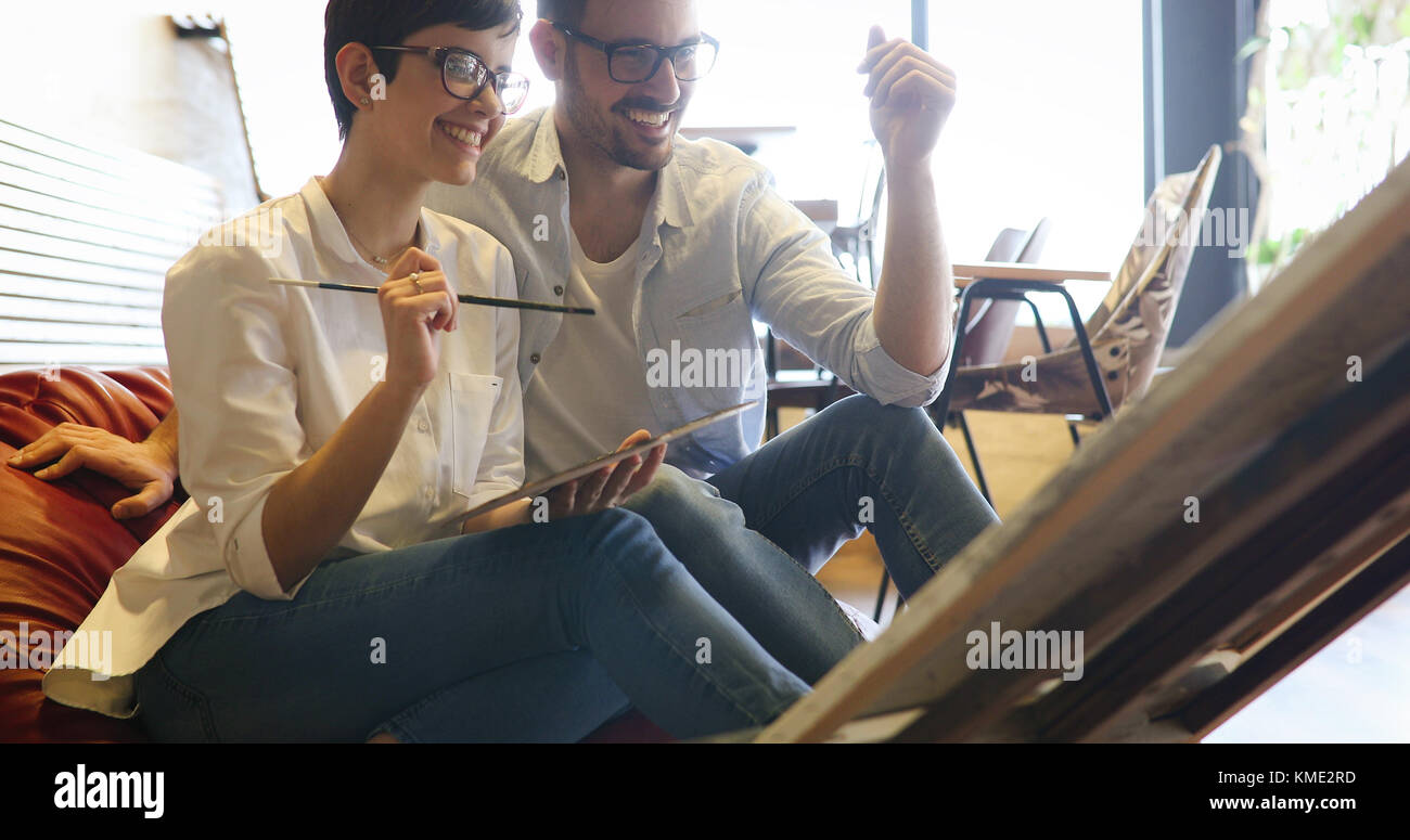 Beautiful young woman and a handsome man attending a painting workshop together Stock Photo