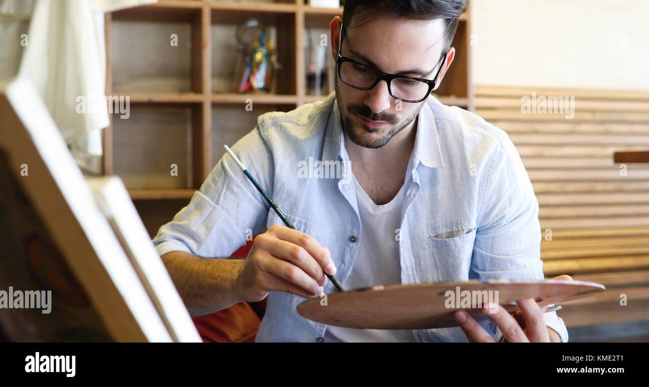 Portrait Of Male Artist Working On Painting In Studio Stock Photo