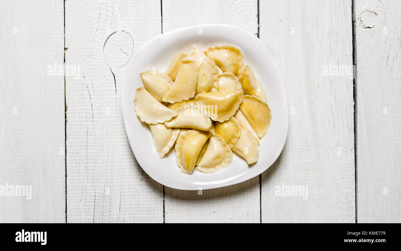 Fresh ravioli with cheese in the plate. On a white wooden background ...