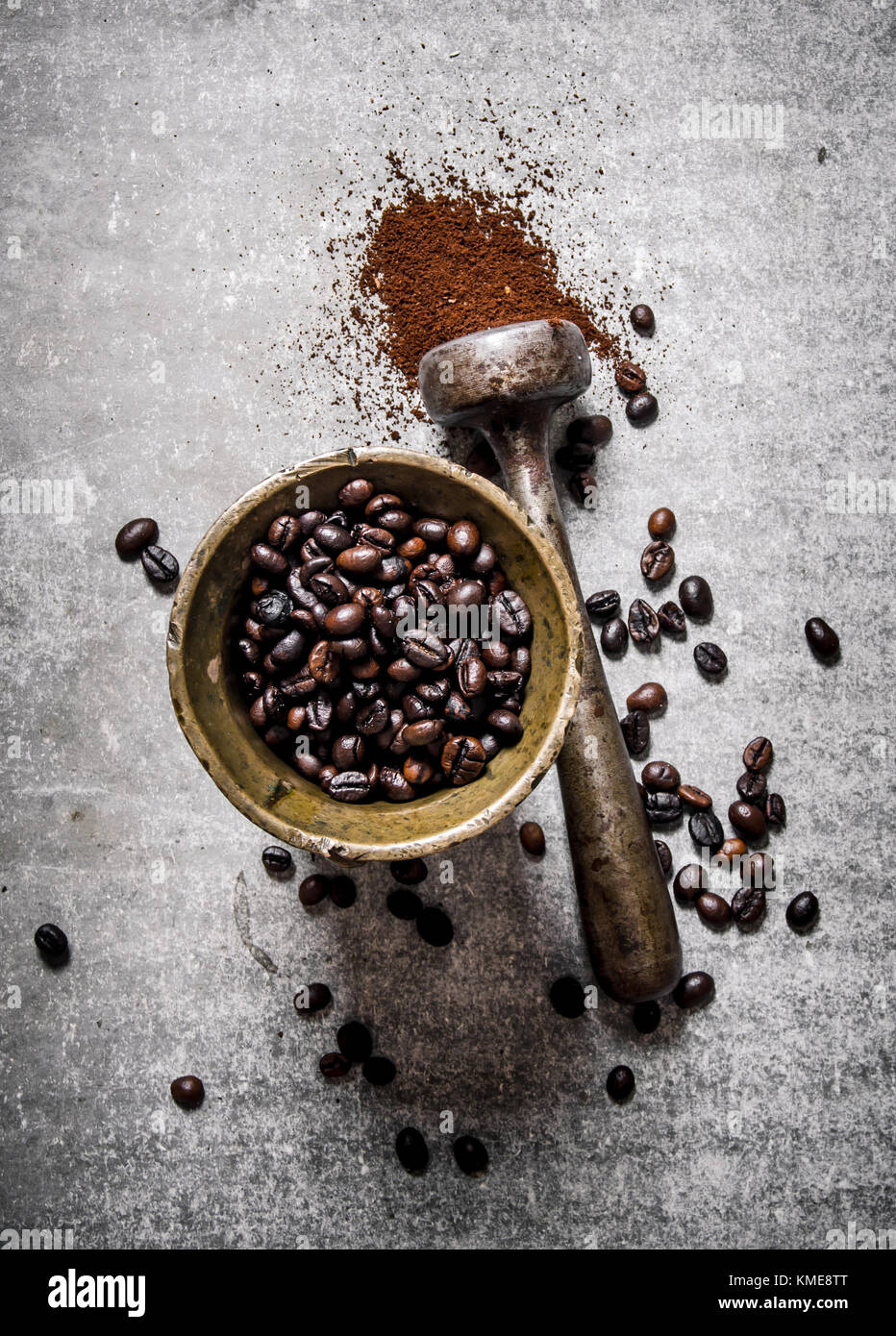 Roasted coffee beans in a mortar with pestle. On a stone background