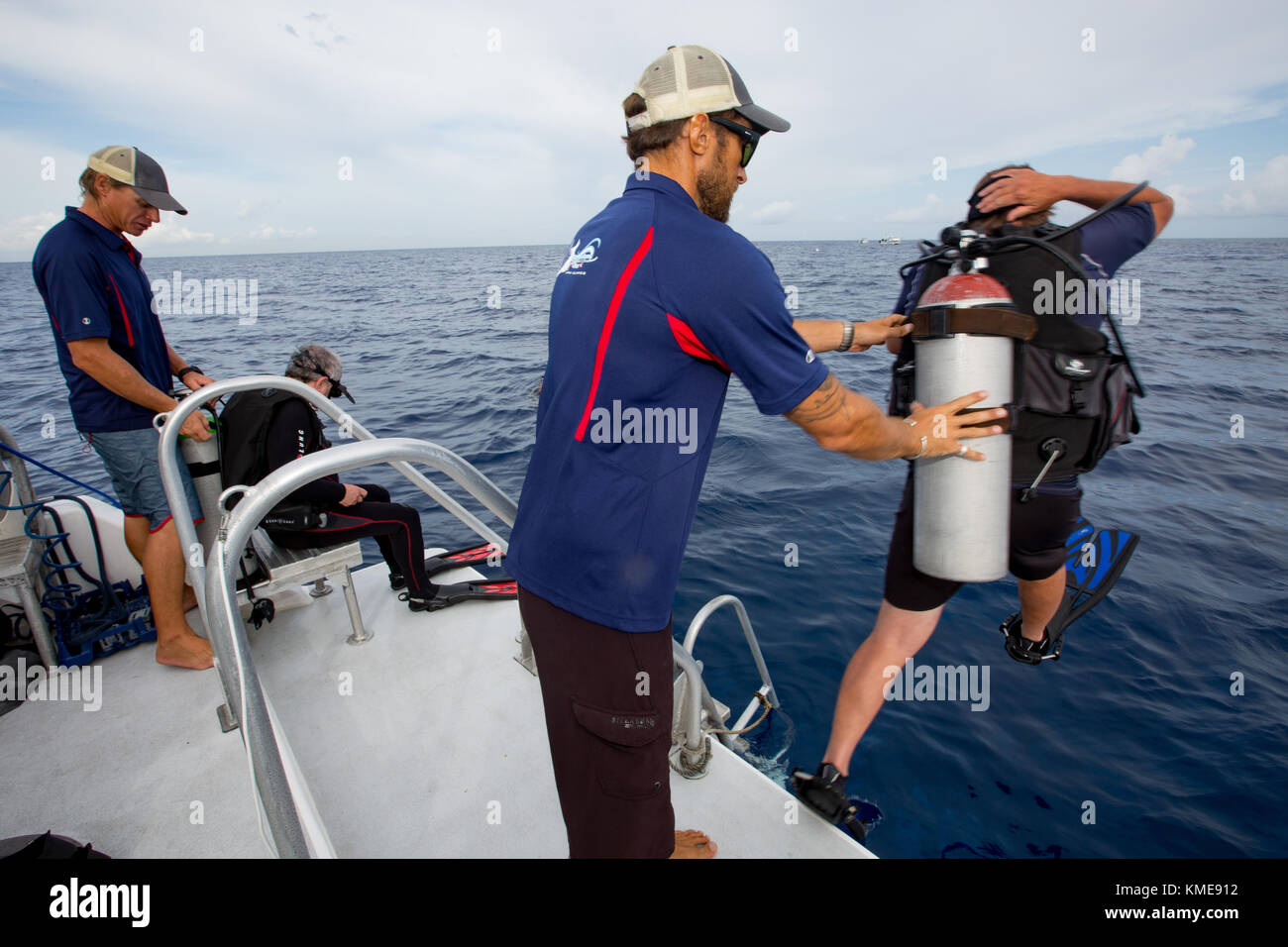 Boat crew assists scuba divers entering water Stock Photo