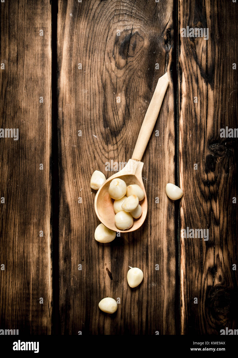 Peeled cloves of garlic in a wooden spoon. On wooden background Stock ...