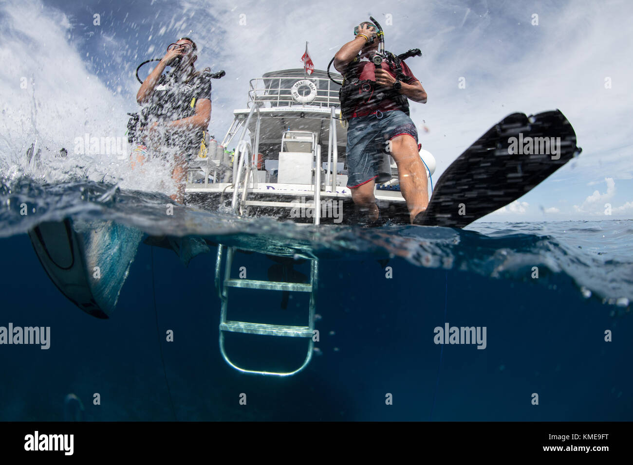 Scuba divers enter water doing giant stride. Stock Photo
