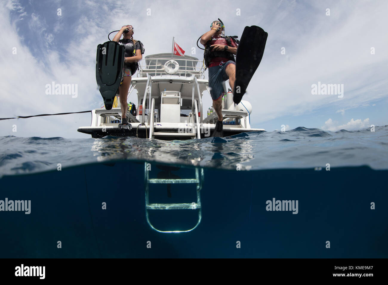 Scuba divers enter water doing giant stride. Stock Photo