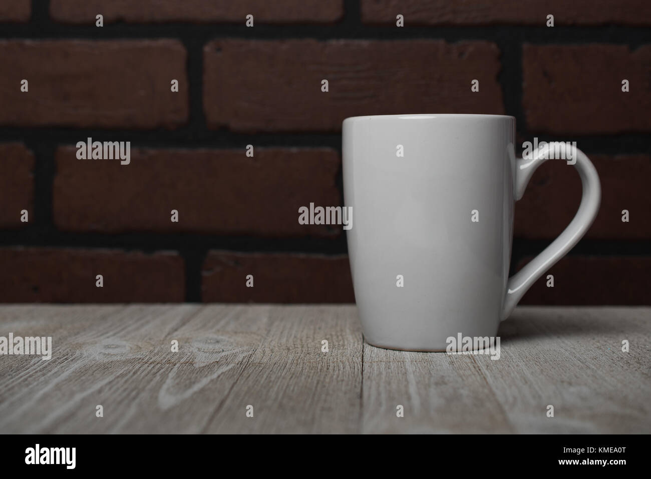 White coffee cup on a white wooden table with brick background Stock Photo