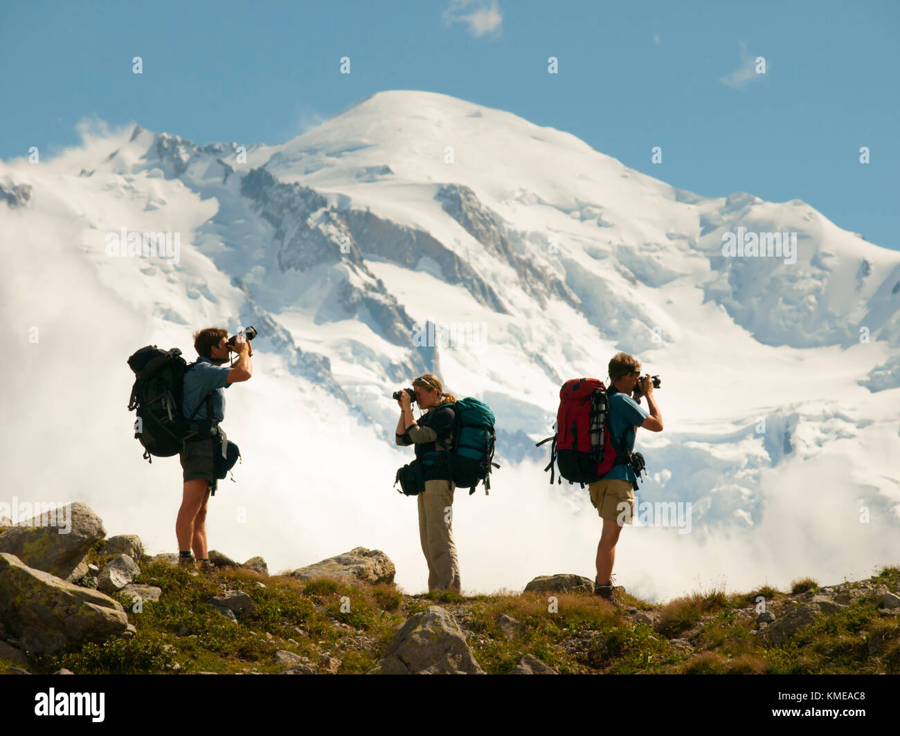 Three hikers taking pictures of French Alps with Mont Blanc in background,Chamonix,Haute-Savoie,France Stock Photo