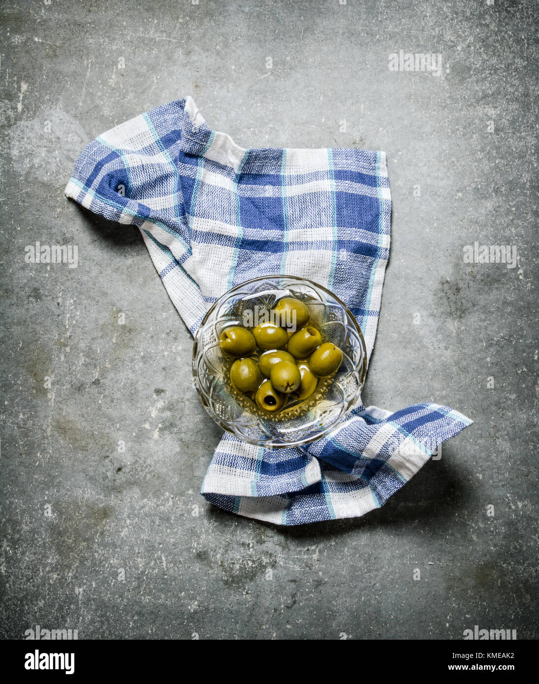 Olives in oil on a glass saucer. On a stone background Stock Photo Alamy